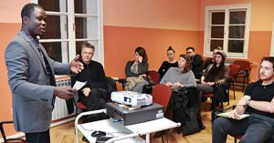 In un'aula di formazione un insegnante di origine africana parla ad un gruppo di persone